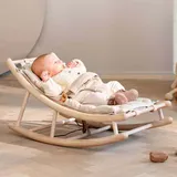 Bebé recostado en la mecedora nórdica de madera con cojín beige