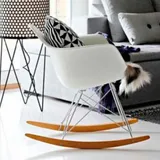 Mecedora estilo Eames blanca en una sala nórdica con cojín geométrico