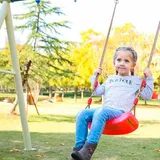 Niña columpiándose al aire libre en el columpio de asiento rojo
