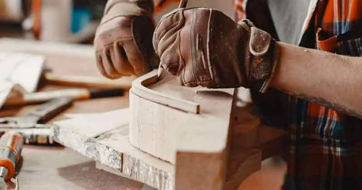 Manos de un carpintero trabajando una pieza de madera en el taller